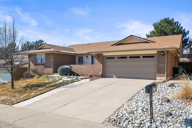 ranch-style house featuring an attached garage, fence, concrete driveway, and brick siding