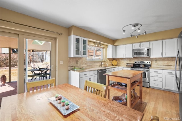 4621 S Perry Way, Denver, CO 80236 - kitchen with appliances with stainless steel finishes, white cabinetry, light wood-style flooring, and backsplash