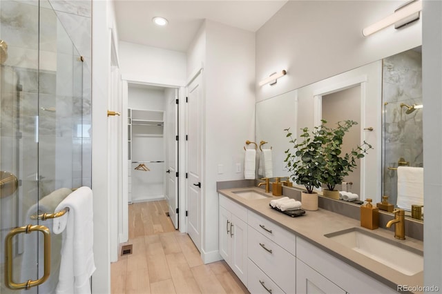 bathroom with hardwood / wood-style floors, vanity, and a shower with shower door