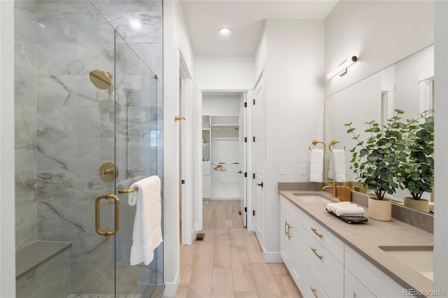 bathroom with a shower with shower door, vanity, and wood-type flooring