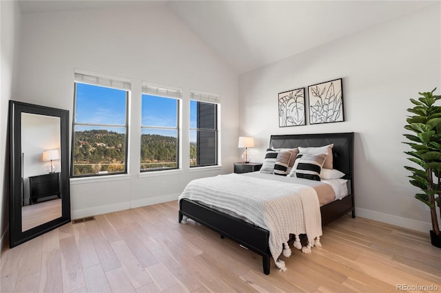 bedroom featuring high vaulted ceiling and light hardwood / wood-style floors