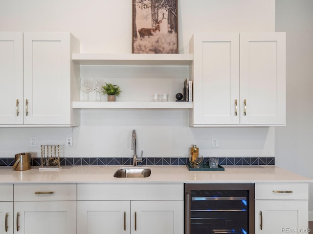 interior space with beverage cooler, sink, and white cabinetry