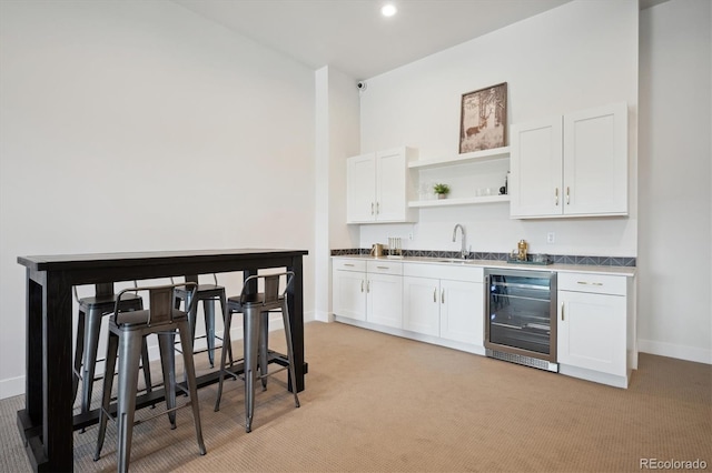 kitchen featuring white cabinets, light colored carpet, and wine cooler