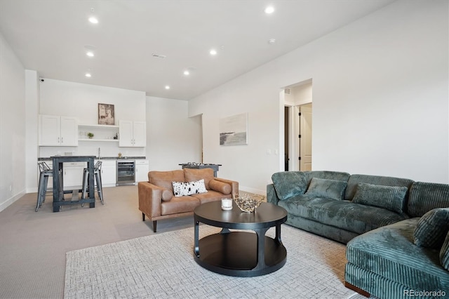 carpeted living room with beverage cooler and sink