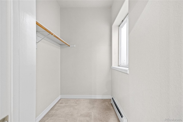 spacious closet with a baseboard heating unit and light colored carpet