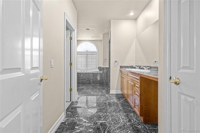 full bath with marble finish floor, recessed lighting, vanity, a tub with marble appearance, and baseboards