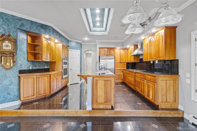 kitchen featuring appliances with stainless steel finishes, decorative light fixtures, a kitchen island with sink, wall chimney range hood, and granite finish floor