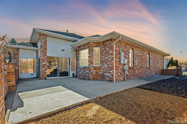 back of property with a patio area, brick siding, and driveway