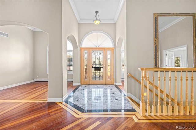 foyer entrance featuring a baseboard heating unit, crown molding, baseboards, and wood finished floors