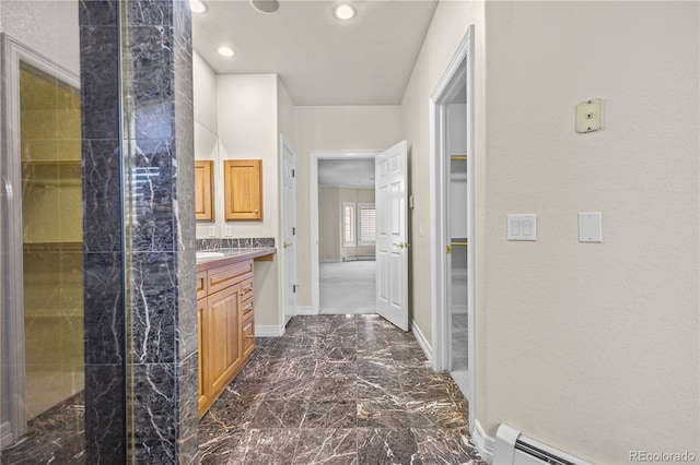 full bath featuring marble finish floor, a spacious closet, baseboard heating, vanity, and baseboards