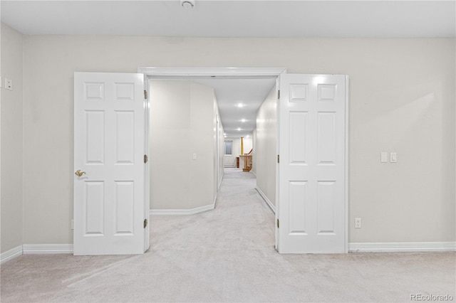 unfurnished room featuring light carpet and baseboards