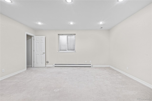 spare room with a baseboard heating unit, light carpet, baseboards, and recessed lighting