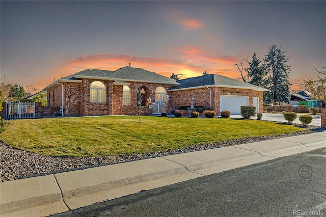 view of front of house featuring brick siding, concrete driveway, a lawn, an attached garage, and fence