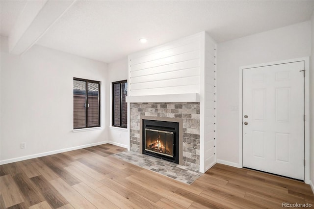 unfurnished living room with hardwood / wood-style floors, a fireplace, and beamed ceiling