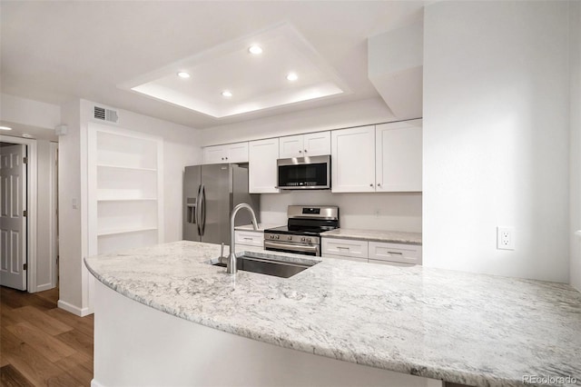 kitchen featuring stainless steel appliances, kitchen peninsula, sink, and white cabinets