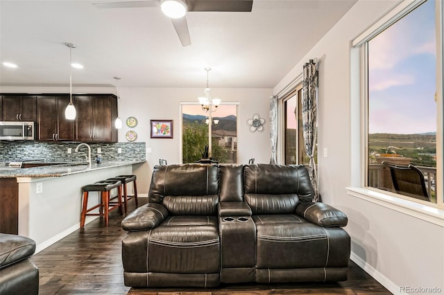 living room featuring dark wood-type flooring and ceiling fan with notable chandelier