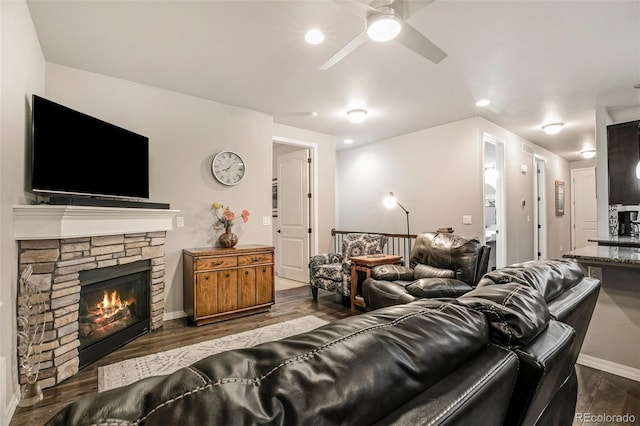 living room with a stone fireplace, hardwood / wood-style flooring, and ceiling fan