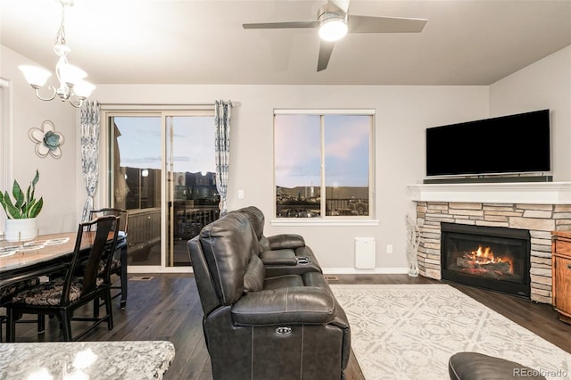 living room featuring ceiling fan with notable chandelier, a fireplace, and dark hardwood / wood-style floors