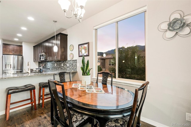 dining space featuring sink, dark hardwood / wood-style flooring, and a chandelier