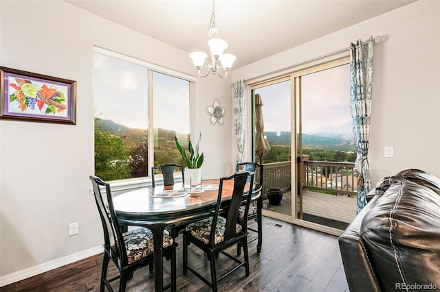 dining area with a mountain view, an inviting chandelier, a wealth of natural light, and dark hardwood / wood-style floors