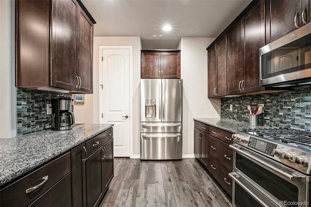 kitchen featuring light stone counters, stainless steel appliances, wood-type flooring, and dark brown cabinets