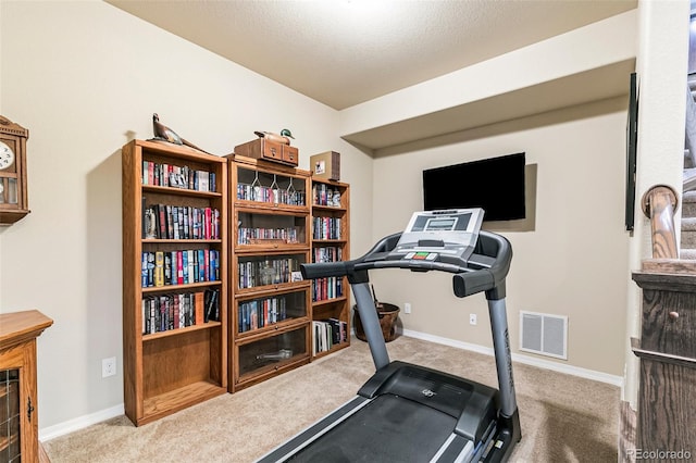 workout room with a textured ceiling and light colored carpet