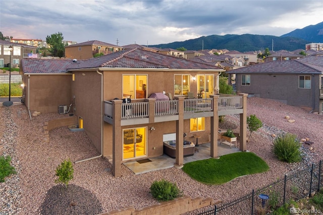 back of house with a patio, a mountain view, a hot tub, and a balcony