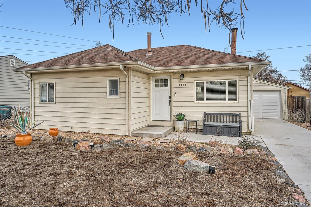 view of front of property with a garage, roof with shingles, concrete driveway, and fence