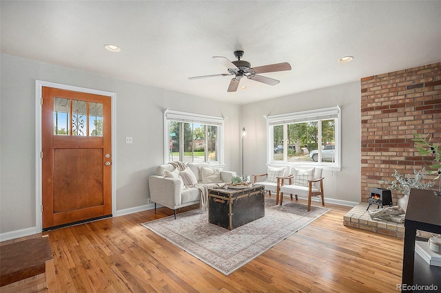 living room featuring a wood stove, light hardwood / wood-style floors, and ceiling fan