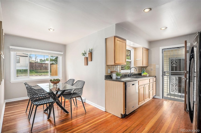 kitchen with light brown cabinets, sink, tasteful backsplash, stainless steel dishwasher, and light hardwood / wood-style flooring