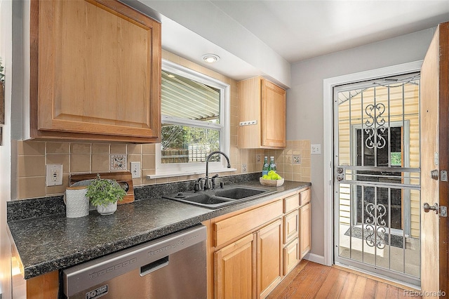 kitchen featuring tasteful backsplash, dishwasher, light hardwood / wood-style flooring, dark stone counters, and sink