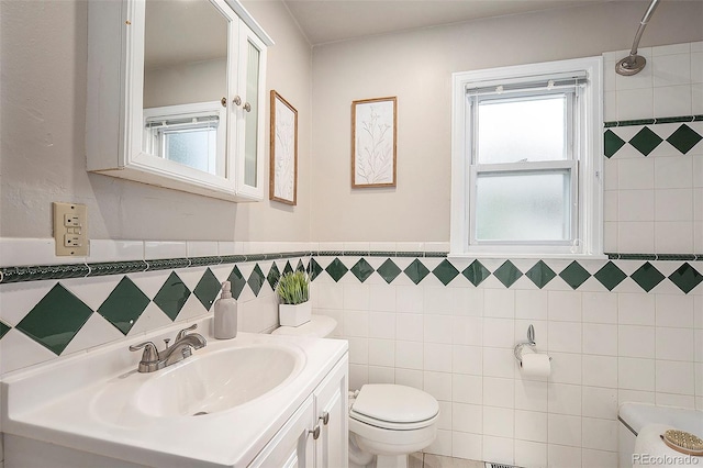 bathroom featuring vanity, tile walls, and toilet