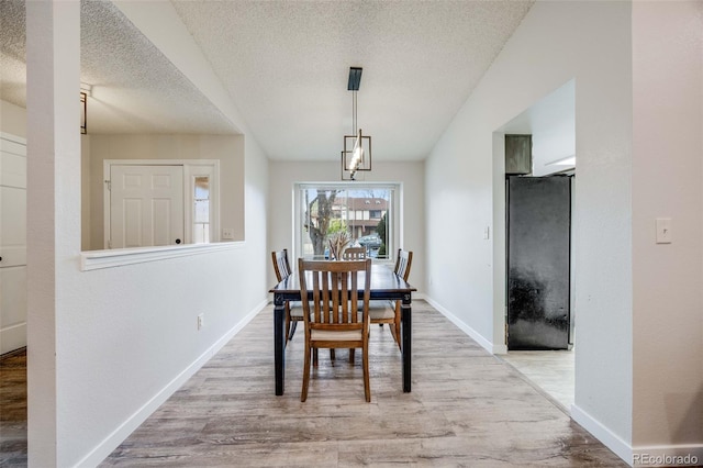 dining space with a textured ceiling, baseboards, and wood finished floors
