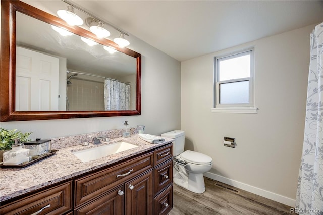 bathroom with visible vents, wood finished floors, baseboards, vanity, and toilet