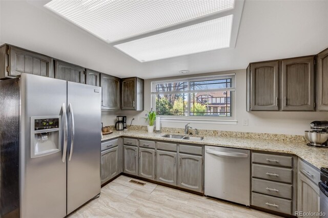 14867 E Pacific Pl, Aurora, CO 80014 - kitchen featuring a sink, light stone counters, visible vents, dark brown cabinetry, and appliances with stainless steel finishes