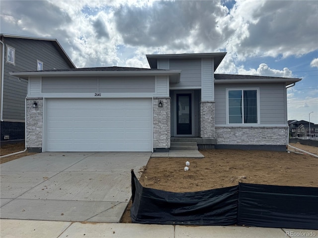 2141 S Irvington St, Aurora, CO 80018 - view of front facade with stone siding, driveway, an attached garage, and entry steps