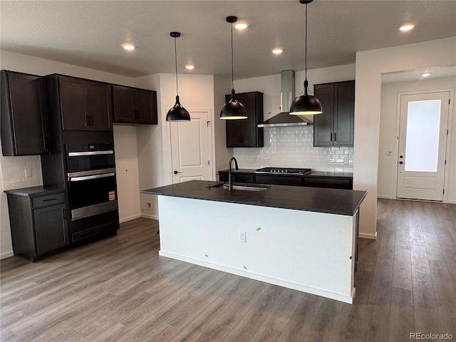 2141 S Irvington St, Aurora, CO 80018 - kitchen featuring wall chimney range hood, dark countertops, appliances with stainless steel finishes, wood finished floors, and recessed lighting