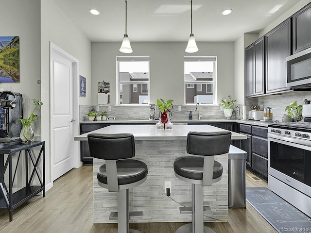 4245 E Iliff Ave Unit 2, Denver, CO 80222 - kitchen featuring backsplash, appliances with stainless steel finishes, a breakfast bar area, and light countertops
