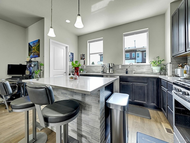 4245 E Iliff Ave Unit 2, Denver, CO 80222 - kitchen featuring decorative backsplash, a sink, stainless steel appliances, and light wood-style flooring