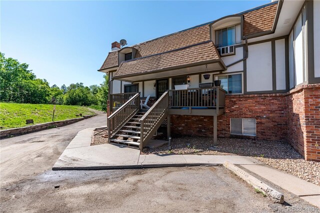 2700 S Holly St Unit 115, Denver, CO 80222 - view of front facade featuring a chimney, roof with shingles, mansard roof, brick siding, and a porch