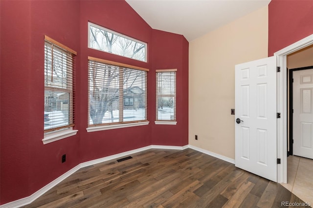 spare room with hardwood / wood-style floors and high vaulted ceiling