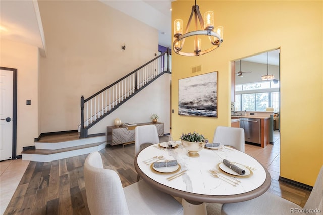 dining space featuring a high ceiling, an inviting chandelier, and light hardwood / wood-style flooring