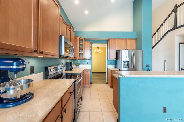 kitchen with appliances with stainless steel finishes, hanging light fixtures, high vaulted ceiling, a notable chandelier, and light tile patterned flooring