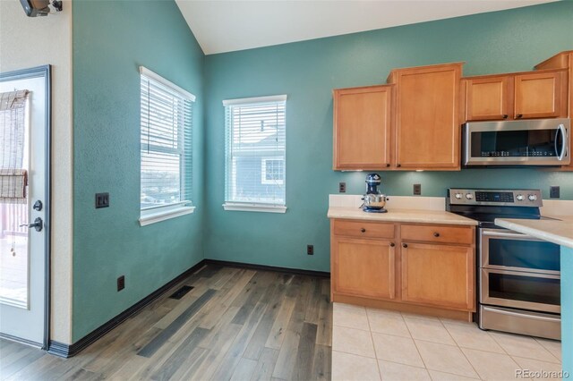 kitchen with stainless steel appliances, lofted ceiling, and light hardwood / wood-style flooring