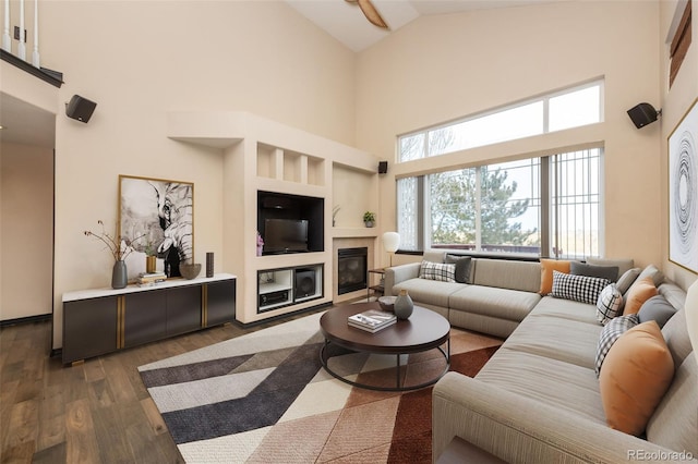 living room with a tile fireplace, dark wood-type flooring, and high vaulted ceiling