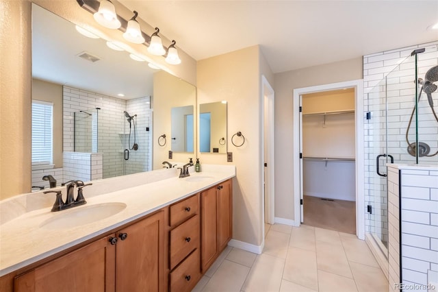 bathroom with a shower with door, vanity, and tile patterned flooring