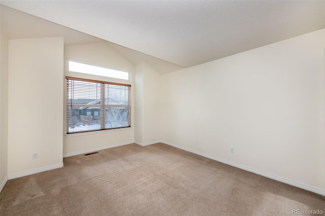 carpeted spare room featuring vaulted ceiling