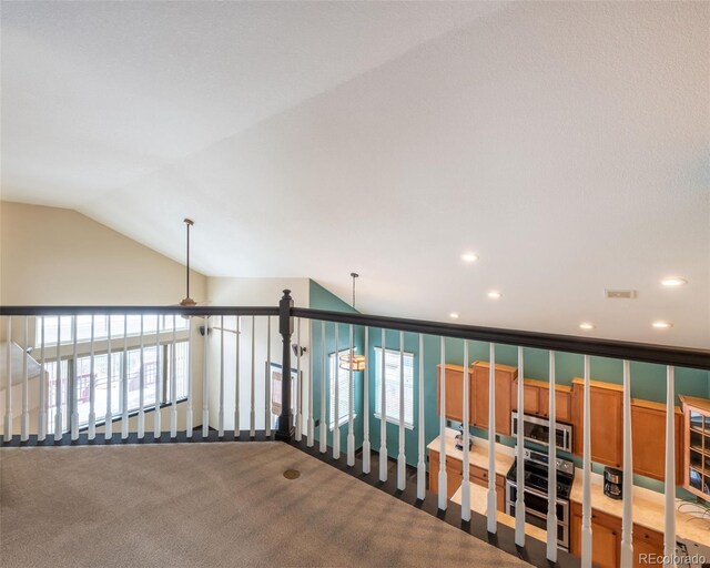 corridor with vaulted ceiling, carpet, and a wealth of natural light