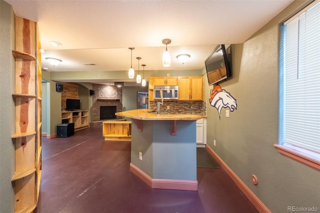 kitchen with pendant lighting, a breakfast bar, tasteful backsplash, an island with sink, and light brown cabinets