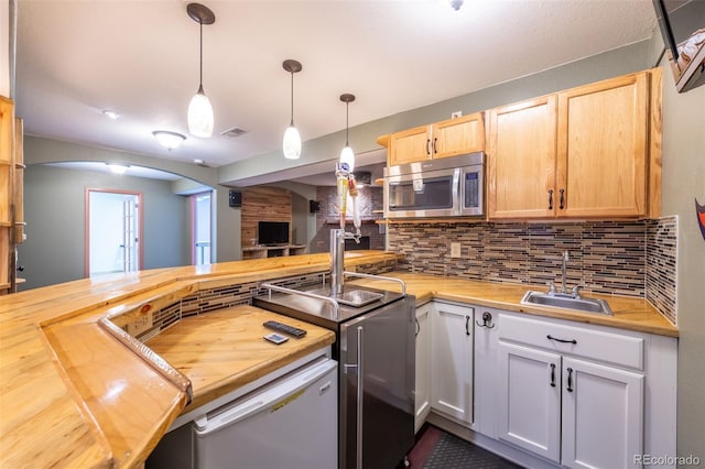 kitchen with hanging light fixtures, sink, wood counters, and kitchen peninsula